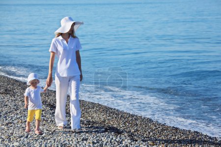 Mother with child walk on edge of sea