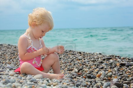 Child sits on pebble beach