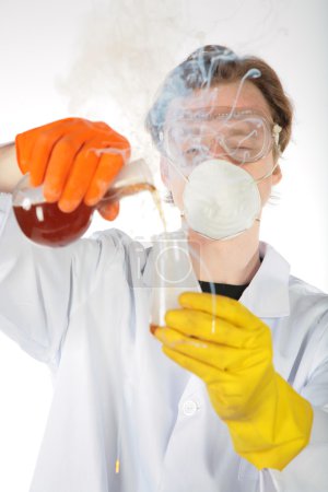 Chemist in smoke pours a liquid in a flask