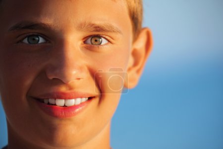 Smiling teenager boy against sea