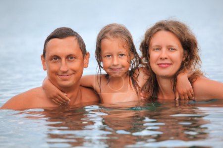Happy family with little girl bathe in sea