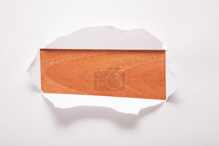 The sheet of paper with the rectangular hole against the wooden background