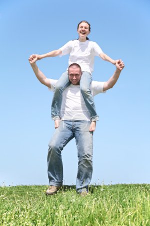 Girl on boy's shoulders on grass