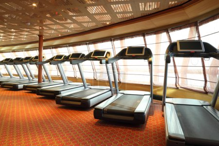 Large gym hall with treadmills near windows in cruise ship
