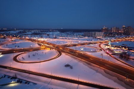 Night winter cityscape with big interchange and lighting columns