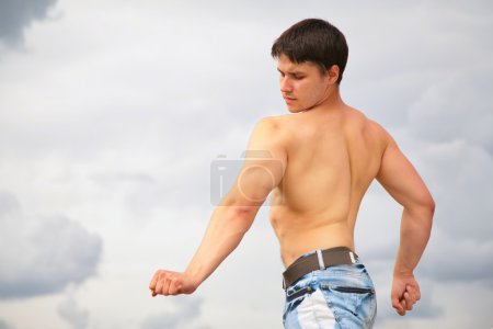Young bodybuilder on cloudy background