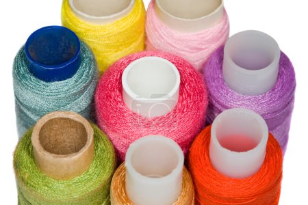 Spools with multi-coloured sewing threads isolated on white back