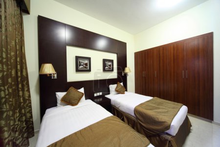 Bedroom with white walls, wardrobe and two beds general view