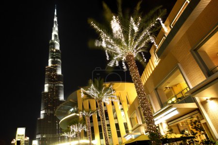 Night Dubai street, palms with decor lamps and Burj Dubai, Unite