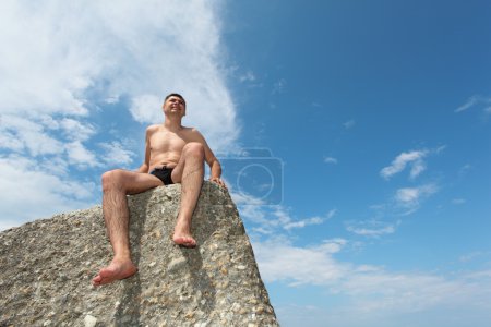 Man sits on rock, bottom view