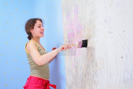 Young woman glues wall-paper