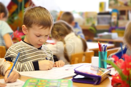 Boy draws in kindergarten