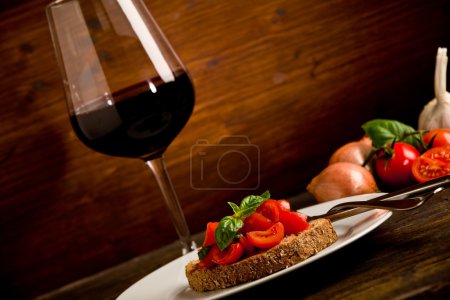 Bruschetta appetizer with red wine on wooden table