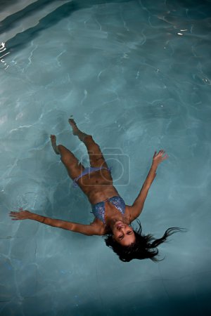 Pretty young lady relaxing in the swimming pool