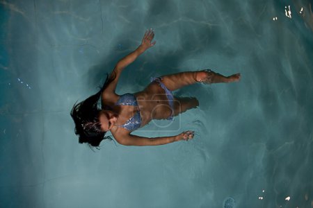 Pretty young lady relaxing in the swimming pool