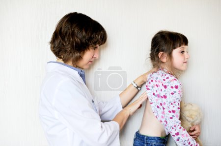Young female doctor examining a little child girl