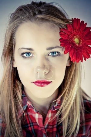 Portrait of young beautiful woman with red flower in her hair