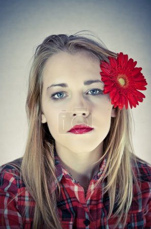 Portrait of young beautiful woman with red flower in her hair