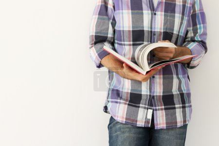 Young man against the wall reading a book