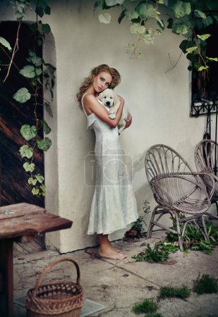 Cute woman in white dress hugging her puppy