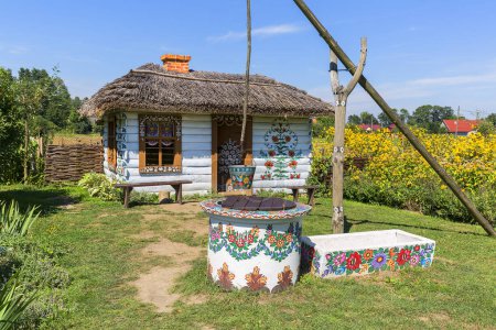 ZALIPIE, POLAND - AUGUST 3, 2018: Painted old wooden cottage, well and pail, decorated with a hand painted colorful floral motives, folk art