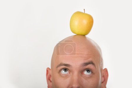 Bald male head with yellow apple