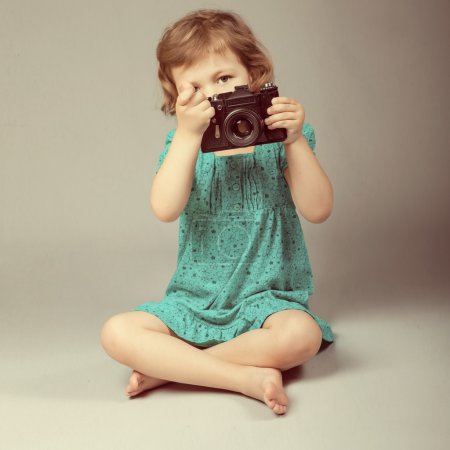 Portrait of baby girl holding photo camera