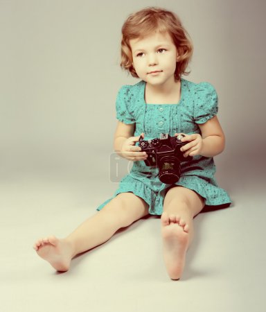 Portrait of baby girl holding photo camera