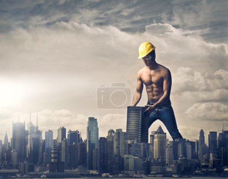 Young brawny worker settling a skyscraper in the skyline of a big city