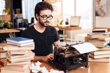 Freelancer bearded man typing at old typewritter sitting at desk.