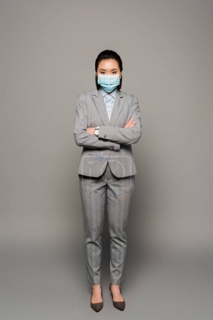 young businesswoman in medical mask on grey background