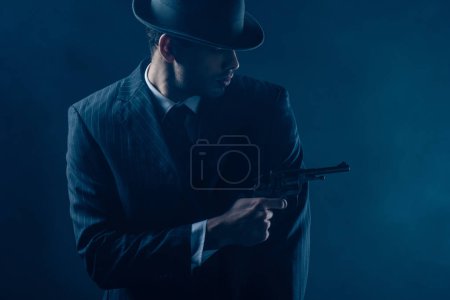 Gangster pointing revolver aside on dark blue background