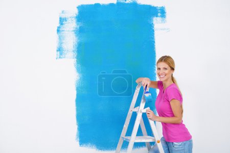 Happy smiling woman painting interior of house
