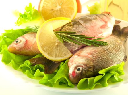 Fresh fish, crucian with a lemon and an onions, salad with olive oil