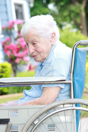 Senior lady in wheel chair in front of house