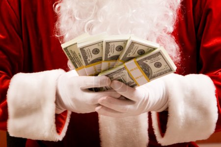 Santa hands with stacks of dollar banknotes