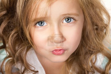 Portrait of little beautiful girl with please in the blue eyes